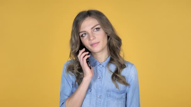 在黄色背景中隔离的智能手机上交谈的年轻女孩 — 图库视频影像