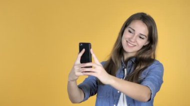 Güzel kadın selfie ile Smartphone üzerinde sarı arka plan izole alarak
