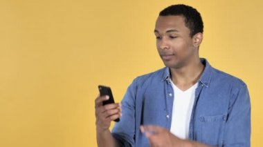 Afrika delikanlı ile Smartphone üzerinde sarı arka plan izole selfie alarak