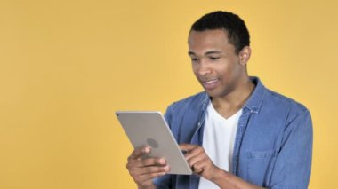 Genç adam African heyecanlı başarı kullanarak Tablet izole sarı arka plan üzerinde süre için