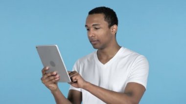 Kaybeden genç Afrika adam şok kullanarak Tablet izole mavi arka plan üzerinde iken