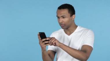 Kaybı için tepki ve üzerinde mavi arka plan izole Smartphone kullanarak Afrika delikanlı