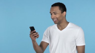 Afrika delikanlı ile Smartphone üzerinde mavi arka plan izole selfie alarak