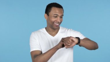 Online Video Chat üzerinde mavi arka plan izole Smartwatch genç Afrika adam tarafından