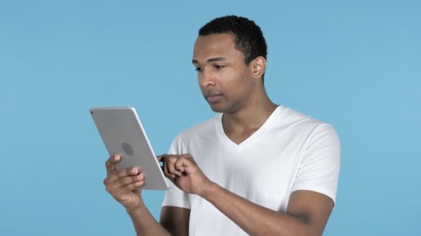 年轻的非洲男人兴奋的成功 而使用平板电脑隔离在蓝色背景 — 图库视频影像