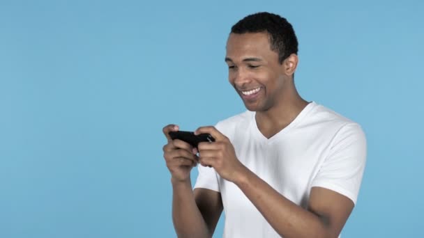 Joven Africano Jugando Juego Smartphone Aislado Fondo Azul — Vídeos de Stock