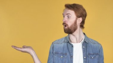 Kızıl saçlı adam gösteren ürün yanında, sarı arka plan