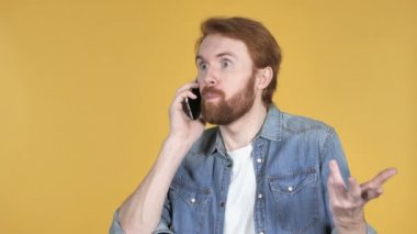 Sarı arka plan üzerinde izole telefonda konuşan heyecanlı Kızıl saçlı adam