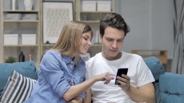 ソファでリラックスしながら若いカップルを使用してスマート フォン メッセージング — ストック動画