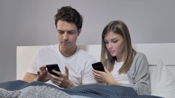 写真のベッドでスマート フォンで Selfie を取ってカップル — ストック動画