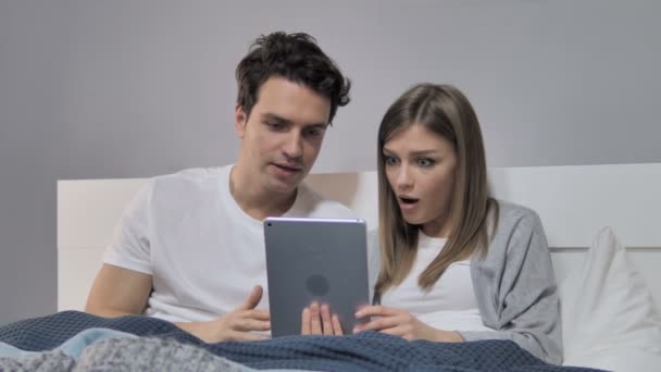 Νέοι Ζευγάρι Πανηγυρίζουν Για Νίκη Ενώ Χρησιμοποιώντας Tablet Στο Κρεβάτι — Αρχείο Βίντεο