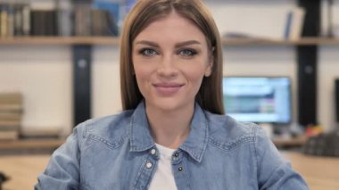 Gülümseyen genç kız kameraya bakıyor.