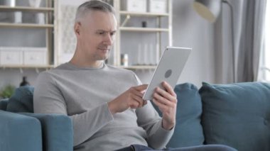 Gri saçlı adam kutluyor başarı kullanarak Tablet ise