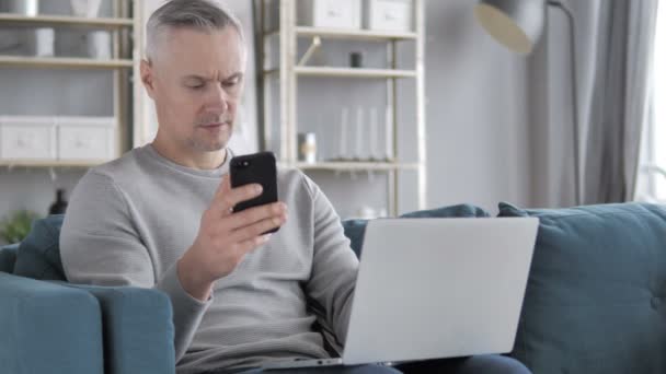 Hombre Pelo Gris Usando Smartphone Laptop Para Trabajo — Vídeo de stock
