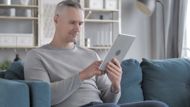 Grått Hår Man Surfar Internet Surfplatta Medan Sitter Soffan — Stockvideo