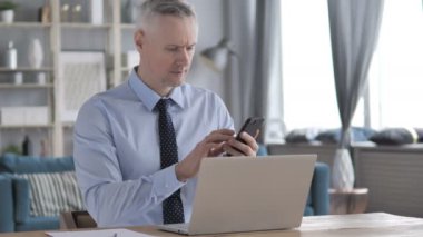 Gri saç işadamı işyerinde Smartphone kullanarak