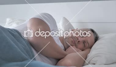 Baş ağrısı, depresif huzursuz gri saçlı adam yatakta uyuyor