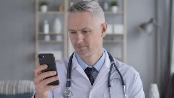 Médico Senior Navegando Teléfono Inteligente — Vídeo de stock