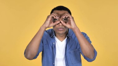 Afrika delikanlı üzerinde sarı arka plan izole el yapımı dürbün ile arama