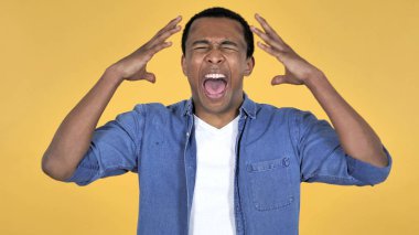 Kızgın genç Afrika adam sarı arka plan üzerinde izole çığlık