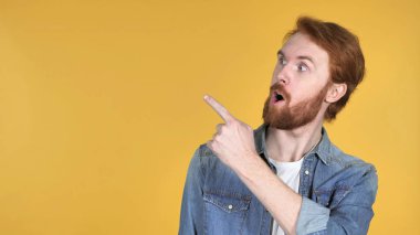 Kızıl saçlı adam parmak tarafında, sarı arka plan ile işaret