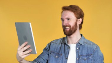 Kızıl saçlı adam sarı arka plan üzerinde izole Tablet ile görüntülü sohbet