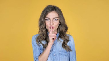 Genç kız sessizlik, dudaklar, sarı arka plan parmağında el hareketi