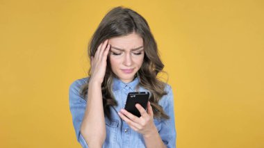 Kaybı için tepki ve sarı zemin üzerine izole Smartphone kullanarak genç kız