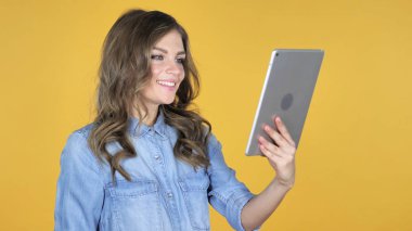 Tablet, sarı arka plan üzerinde genç kız tarafından görüntülü sohbet