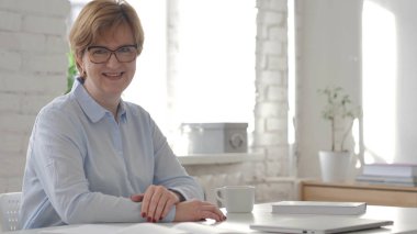 Kameraya bakarak gülümseyen yaşlı kadın