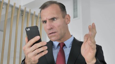 Şaşırmış gibi orta yaşlı işadamı tarafından sonuç Smartphone, şok merak