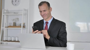Online finansal ticaret için Smartphone kullanarak işadamı orta yaşlı