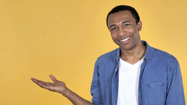 Young African Man Showing Product Side Yellow Background — Stock Photo, Image