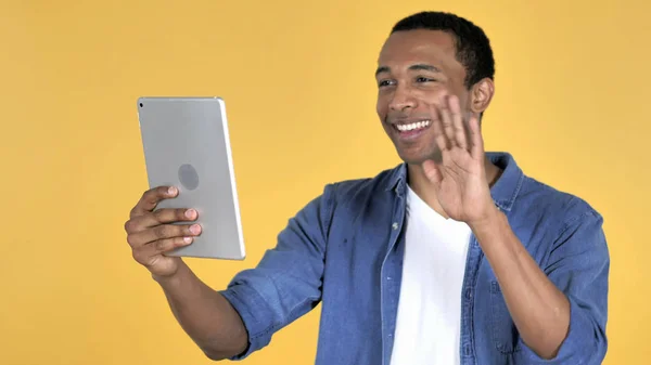 非洲青年通过黄色背景隔离的平板电脑进行视频聊天 — 图库照片
