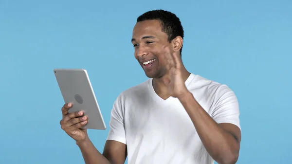 非洲人通过在蓝色背景上隔离的平板电脑进行视频聊天 — 图库照片