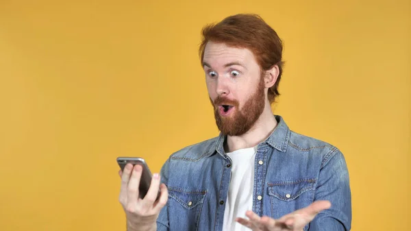 Verbaasd Roodharige Man Verrast Tijdens Het Gebruik Van Smartphone Geïsoleerd — Stockfoto