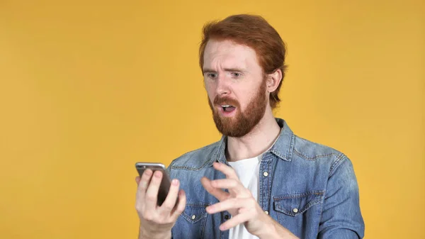 Upset Redhead Man Feeling Desperate While Using Phone Isolated Yellow — Stock Photo, Image