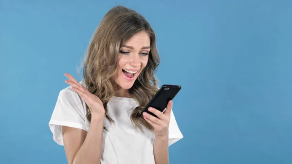 Aamzed Young Girl Excited While Using Smartphone Isolated Blue Background — Stock Photo, Image