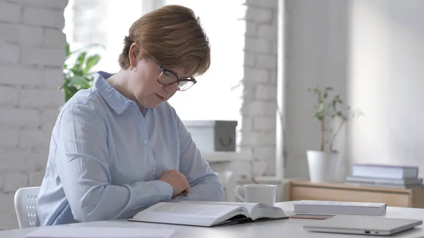 Old Woman Reading Book in Office