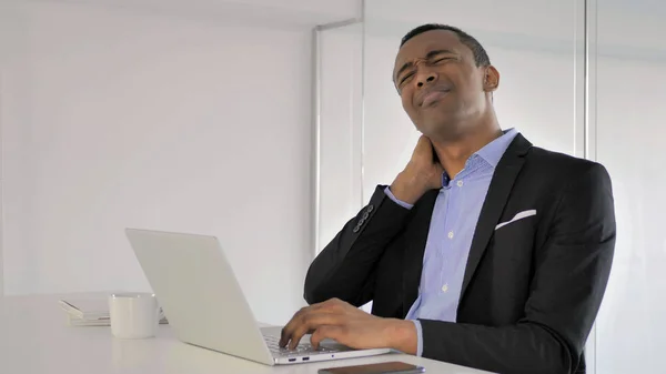 African Businessman with Back Pain working on Laptop