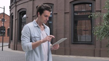 Tablet için Internet kullanan yürüyen adam