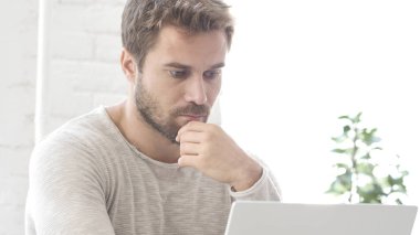 Dizüstü bilgisayarda çalışan sakallı adam düşünme beyin fırtınası