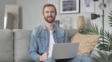 Gülümseyen adam kanepede oturan kamera bakıyor