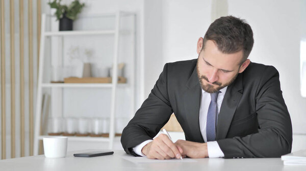 Бизнесмен пишет документы в офисе
