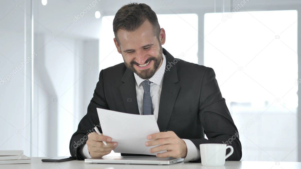 Excited Businessman Celebrating Success while Reading Documents