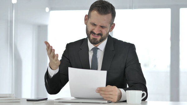Angry Businessman Reacting to Loss while Reading Documents