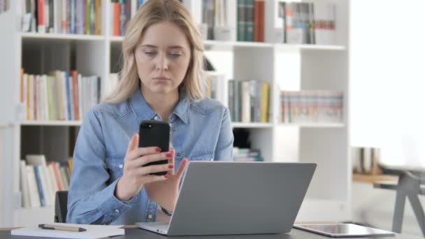 Jonge vrouw met behulp van smartphone voor online werk — Stockvideo