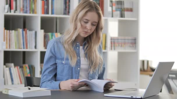 Jovem mulher lendo livro na biblioteca — Vídeo de Stock