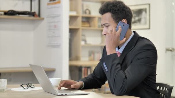 Afrikansk forretningsmann som snakker i telefon og forhandler. – stockvideo