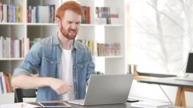 Arka ağrı ile Casual Redhead adam laptop üzerinde çalışıyor